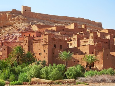 Kasbah Aït Ben Haddou met lemen huizen en palmbomen langs de route van de 14-daagse fietsreis door Marokko.