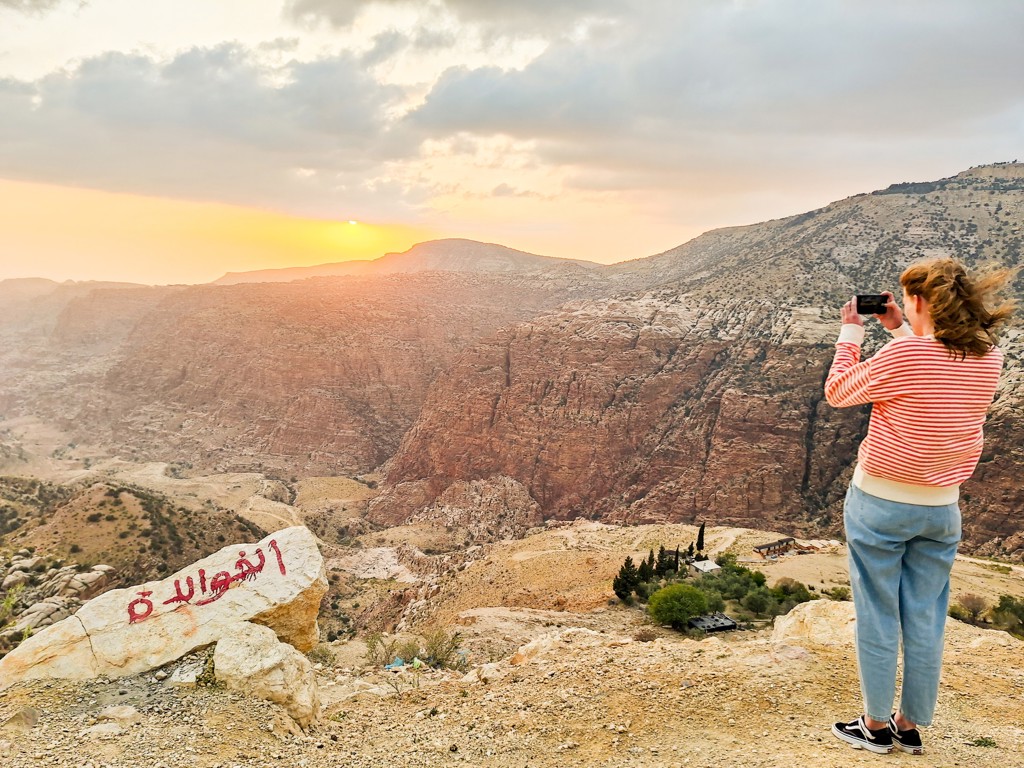 Reiziger fotografeert de zonsondergang boven een bergkloof in Jordanië tijdens een 22-35ers groepsrondreis.