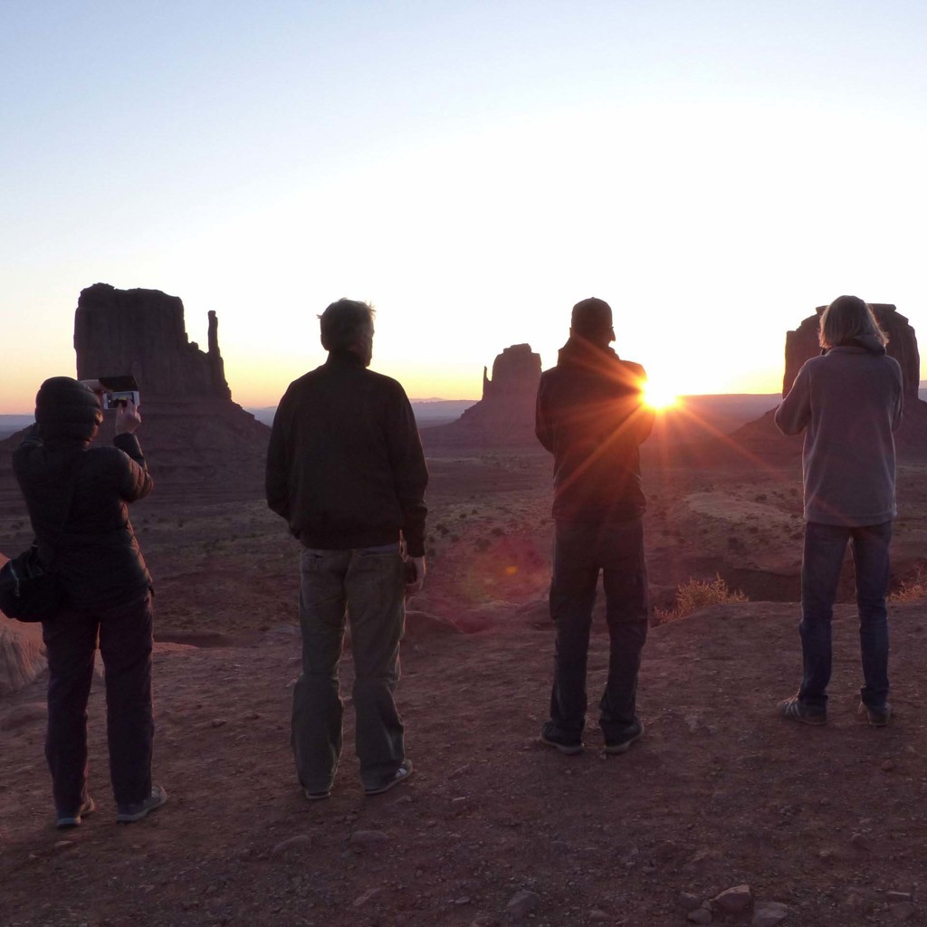 Reizigers kijken naar zonsopkomst bij Monument Valley tijdens groepsrondreis door het Wilde Westen in de VS.