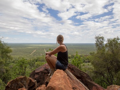 Reiziger op rots met uitzicht over de groene savanne in Namibië tijdens Route Namibië.