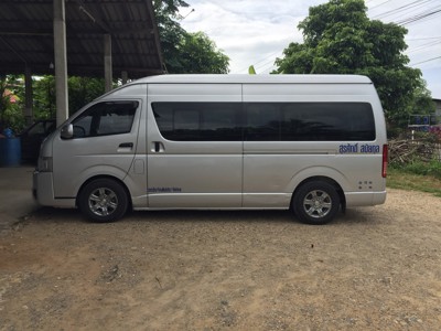 Grijze minivan in Thailand, gebruikt als busje voor vervoer van reizigers.