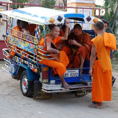 Boeddhistische monniken in oranje gewaden in een tuk-tuk in Laos.