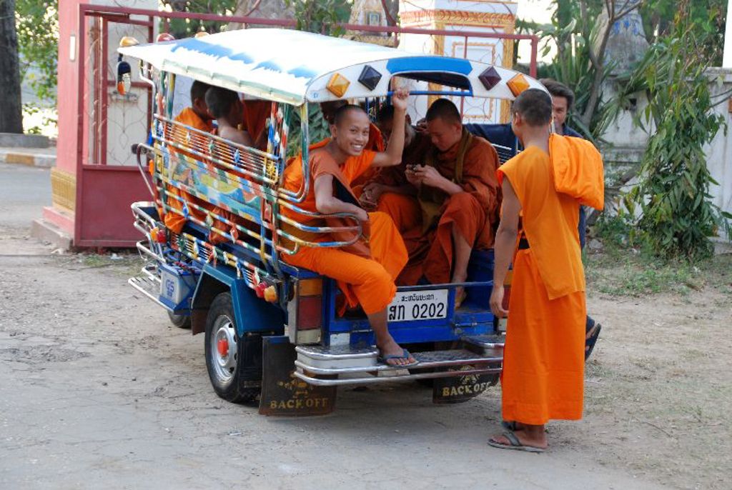 Boeddhistische monniken in oranje gewaden in een tuk-tuk in Laos.