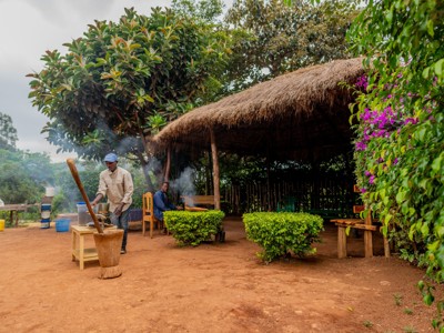 Buitenkeuken met rieten afdak waar een man eten bereidt tijdens Route Oost-Afrika in Kenia en Tanzania.