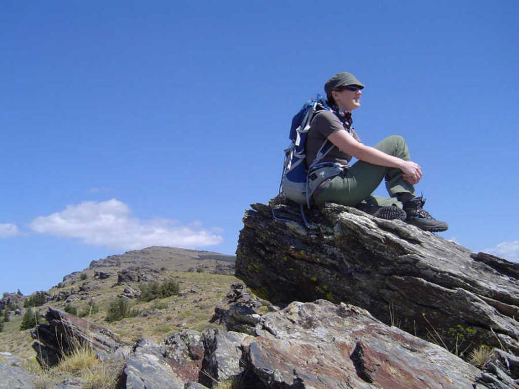Wandelaar met rugzak rust op rots in de Sierra Nevada bij Granada, Spanje.