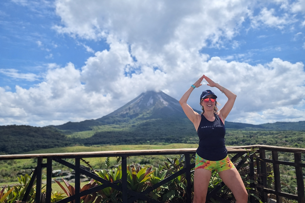 Reiziger poseert op een uitkijkpunt met uitzicht op de Arenal-vulkaan in Costa Rica.