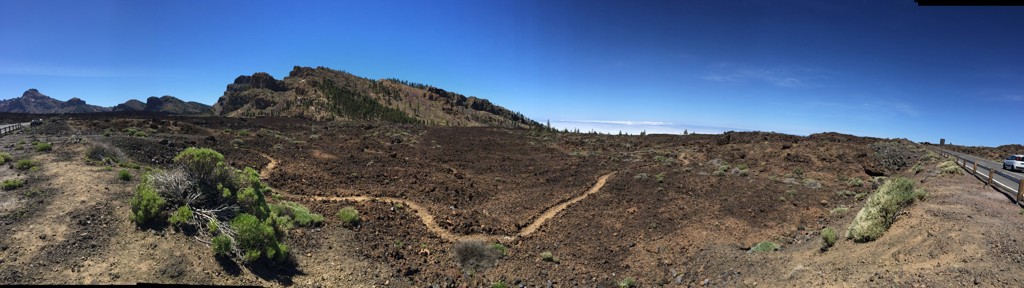 Panorama van het vulkanische landschap bij de Teide op Tenerife, met lavavelden en wandelpad onder blauwe lucht.