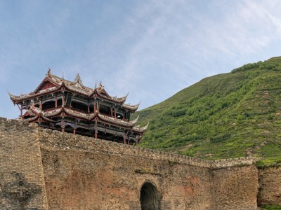 Traditionele Chinese tempel op een stadsmuur in berglandschap tijdens Route China, 32 dagen.