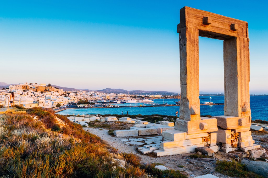 Oude stenen poort bij de kust van Naxos met uitzicht op de haven en witte huizen, Griekenland.