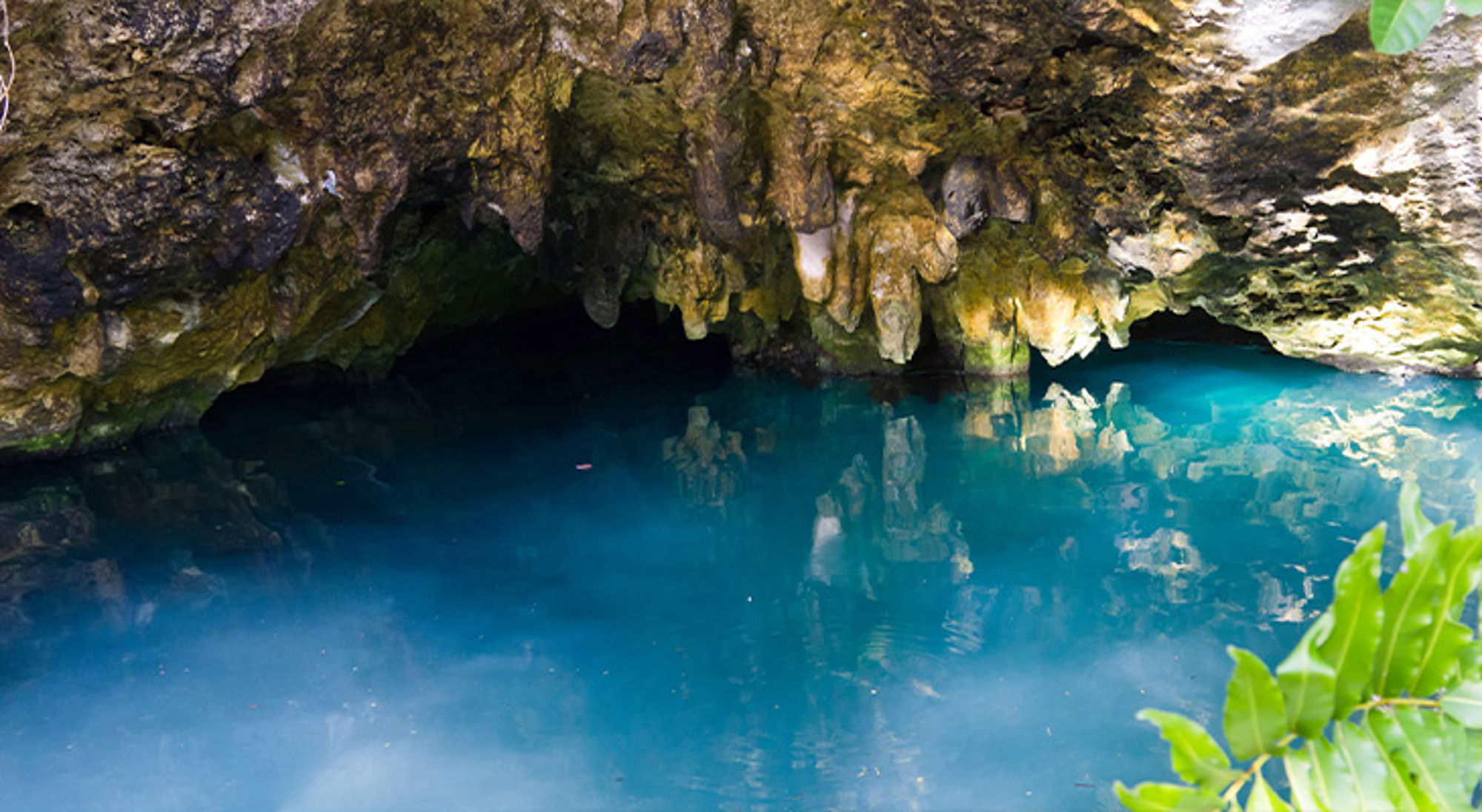 Grande cenote Turquoise water in een grot met stalactieten en rotsformaties.