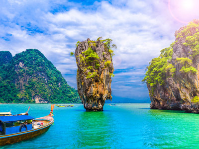 Lange staartboot bij kalkstenen rotsen in Phang Nga Bay, Thailand.