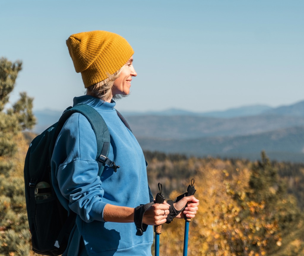 Wandelaar met rugzak en wandelstokken geniet van het uitzicht in de bergen tijdens een wandelvakantie in Albanië.