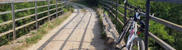 Fiets op brug langs een groene fietsroute, passend bij een fietsvakantie in Slovenië.