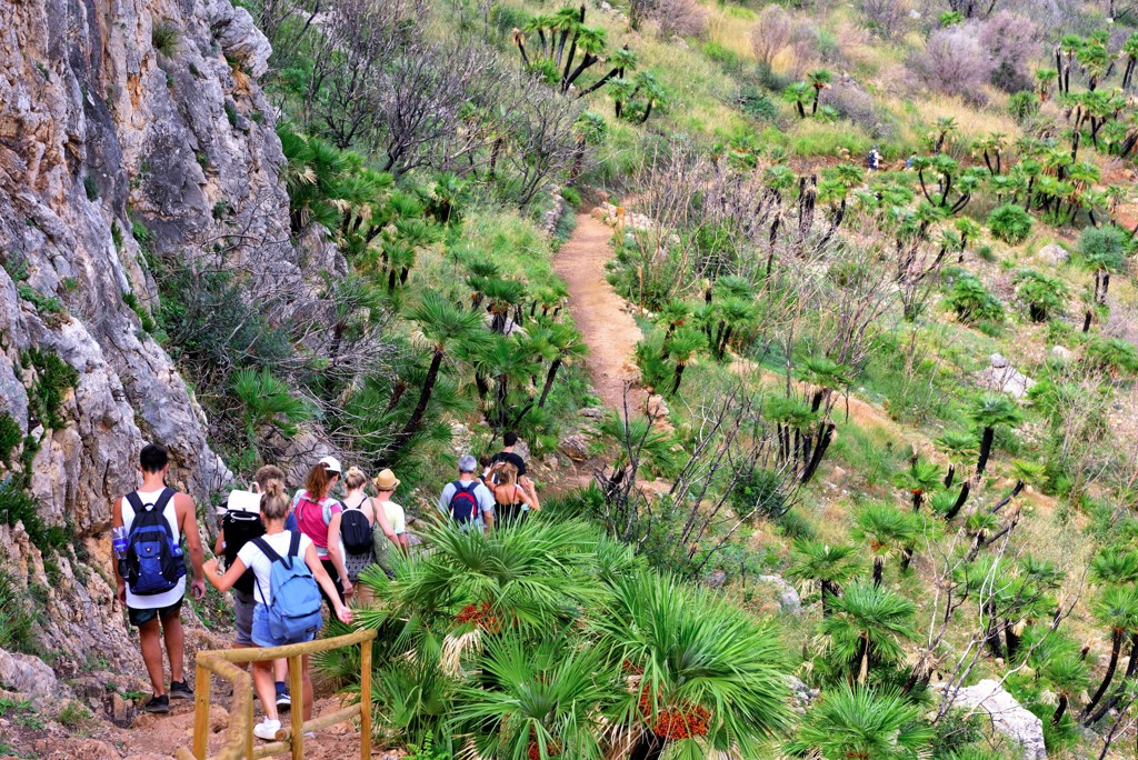 Wandelaars op een bergpad langs rotsen en palmen tijdens een wandelvakantie in West-Sicilië, Italië.