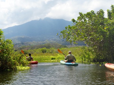 Kajakkers op een rivier met uitzicht op een vulkaan tijdens de route Costa Rica en Nicaragua.