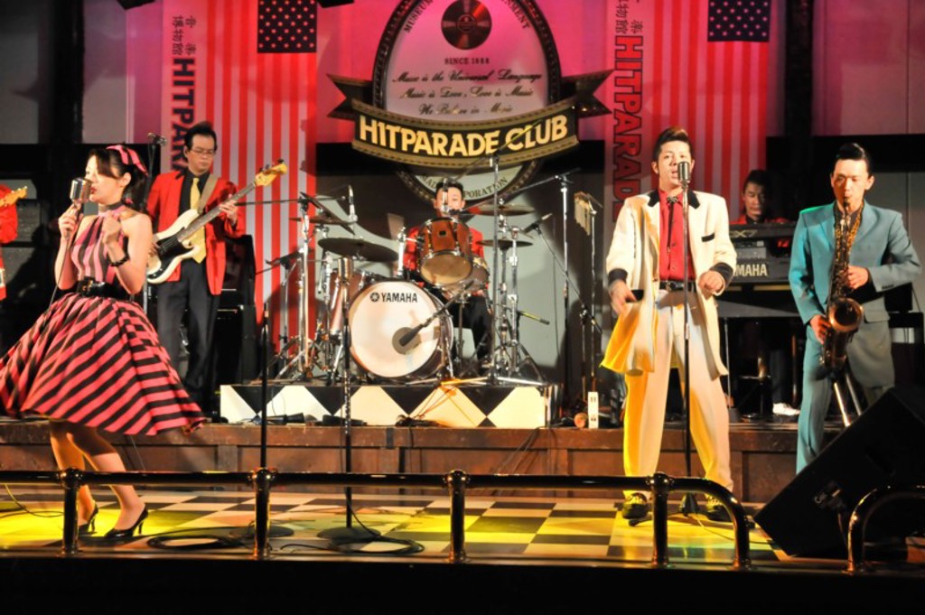 Liveband met zanger en saxofonist op podium met neonverlichting tijdens familiereis Japan.