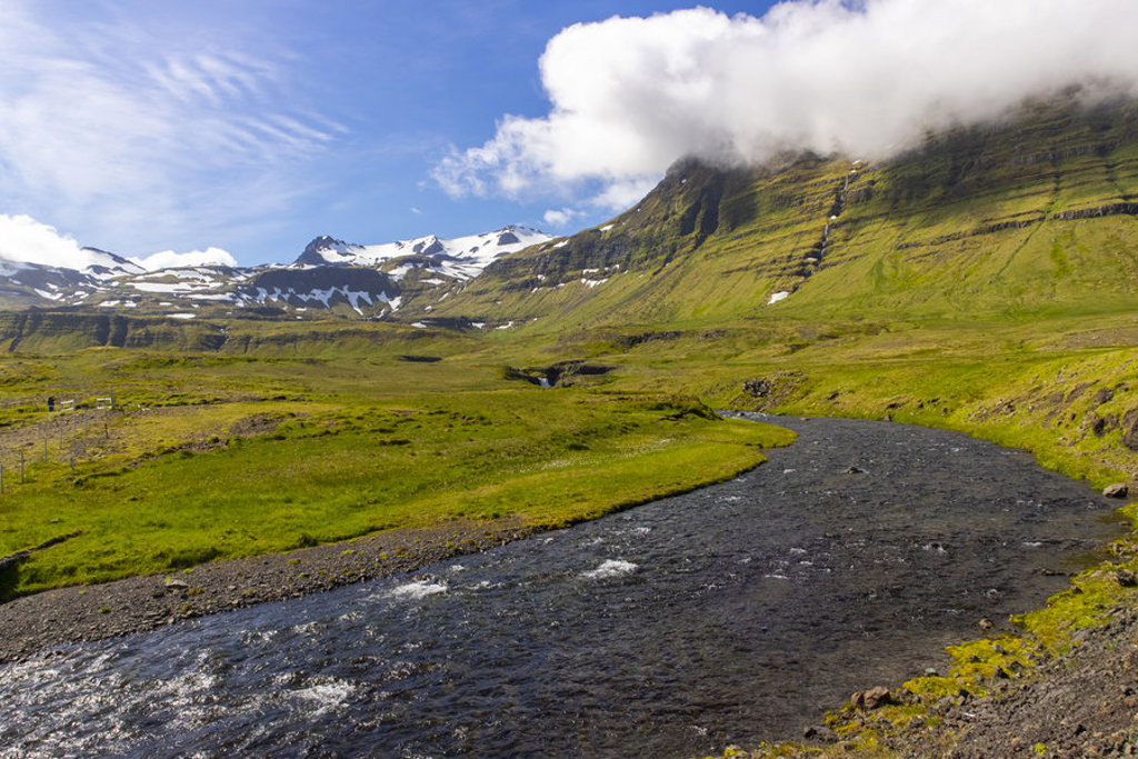 Groene vallei met rivier en besneeuwde bergen in IJsland tijdens groepsrondreis kamperen.