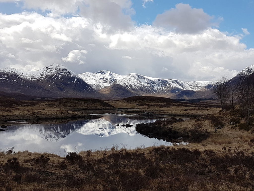 Besneeuwde bergen weerspiegeld in een loch in de Schotse Hooglanden tijdens een groepsrondreis Schotland.
