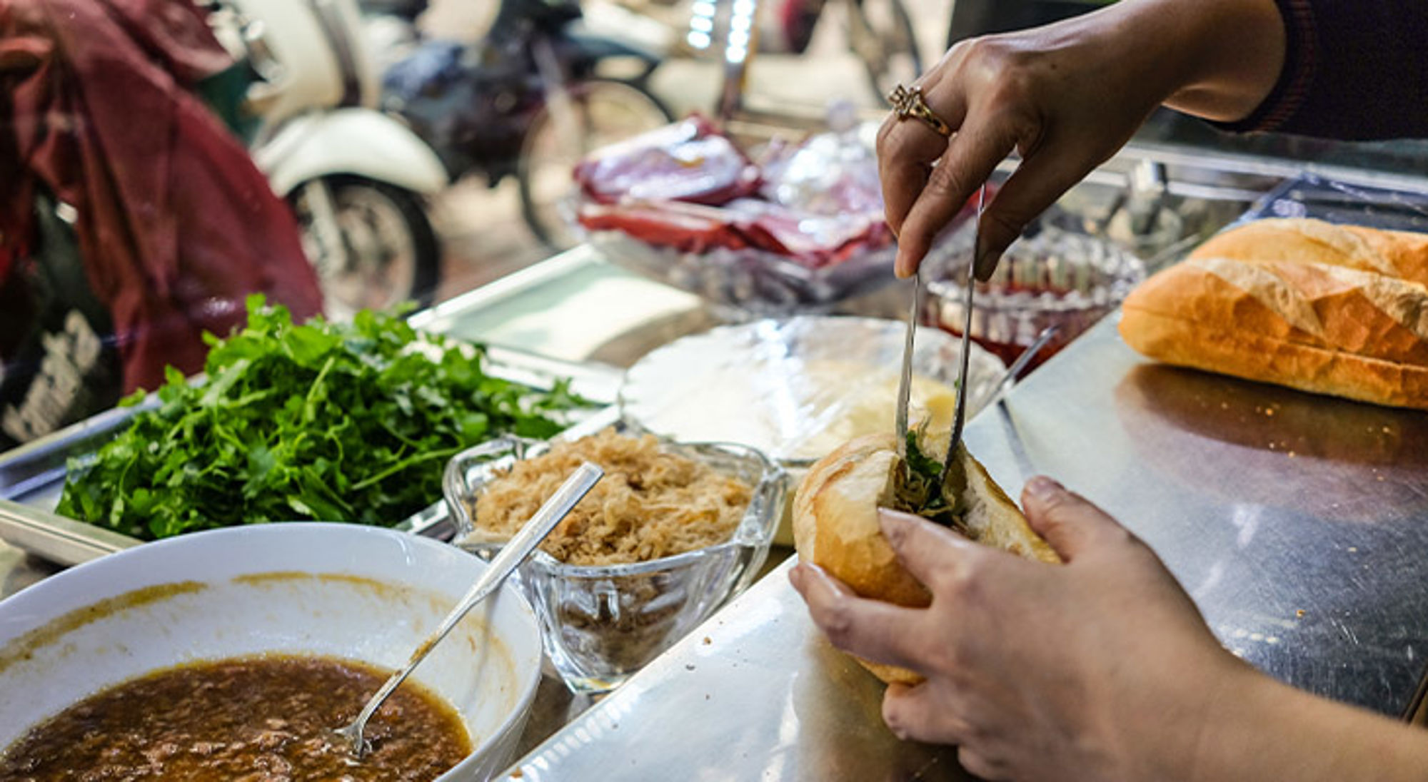Banh mi Vietnam Bereiden van een Vietnamese bánh mì met verse kruiden en saus bij een streetfoodkraam.