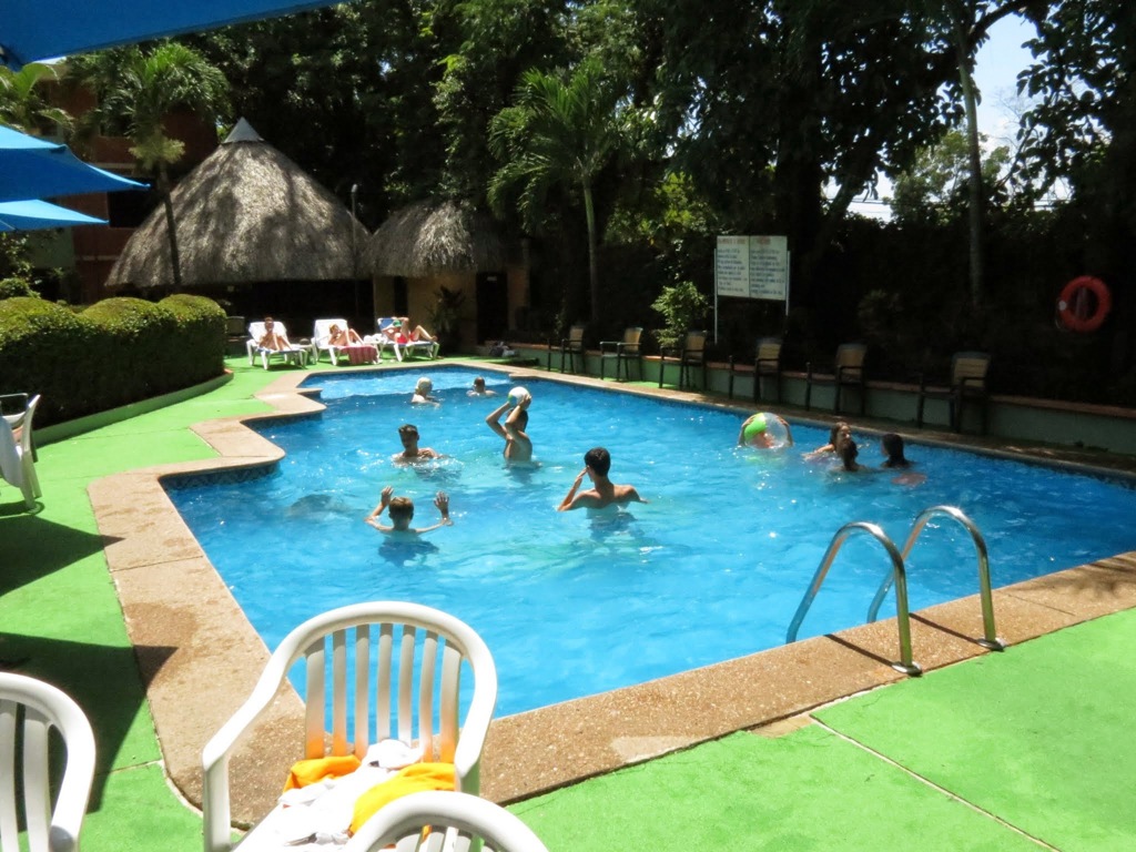 Gezin zwemt in een zwembad bij een lodge in Mexico, omringd door tropisch groen.