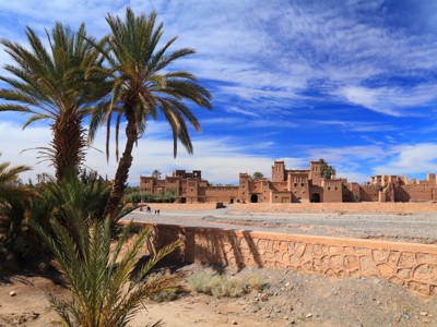 Kasbah van Aït Ben Haddou met palmbomen langs de Route Marokko.
