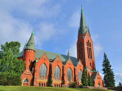 Rode bakstenen kathedraal van Tampere met hoge toren en groene spitsen, Finland.