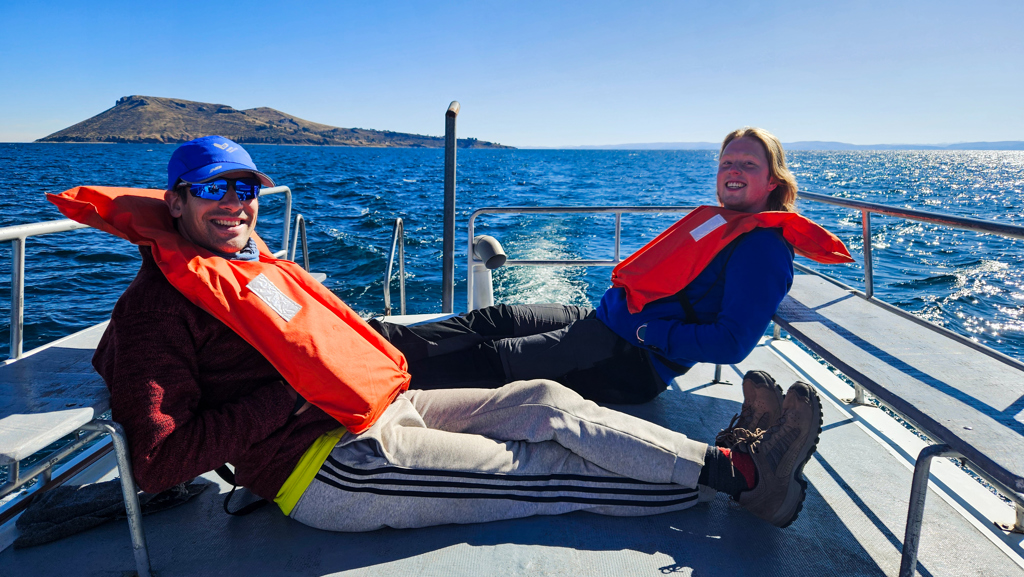 Jongeren relaxen met reddingsvesten op een boot op het Titicacameer in Peru tijdens een 22-35ers groepsrondreis.