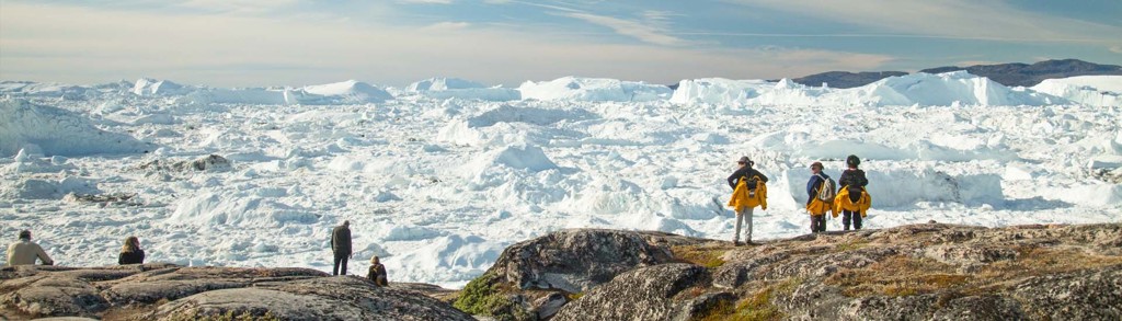 Reizigers kijken uit over het ijslandschap en de ijsbergen van Disko Bay in Groenland.