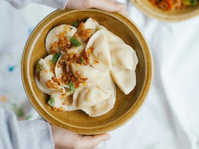 Bord met Russische pelmeni met gebakken ui en dille, onderdeel van de reis Rusland hoogtepunten.