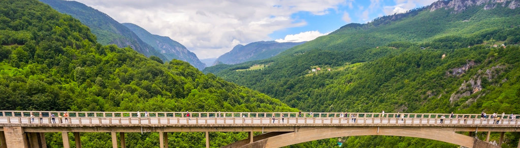 Wandelaars op de Djurdjevica Tara-brug met uitzicht op de groene Tara-kloof in Montenegro.