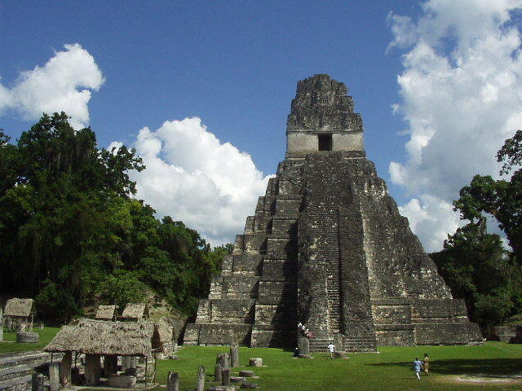 Maya-tempel in Tikal, Guatemala, omringd door jungle onder een blauwe lucht.