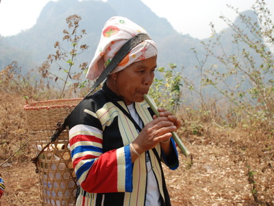 Vrouw in traditionele kleding speelt bamboefluit in de bergen van Thailand tijdens de rondreis Thailand Avontuur, 24 dagen.