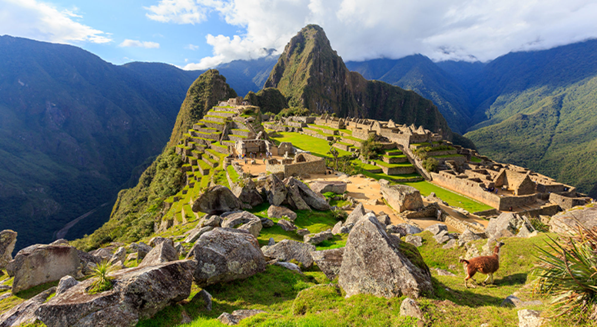 Panoramisch uitzicht op Machu Picchu met Inca-ruïnes en bergen in de achtergrond.
