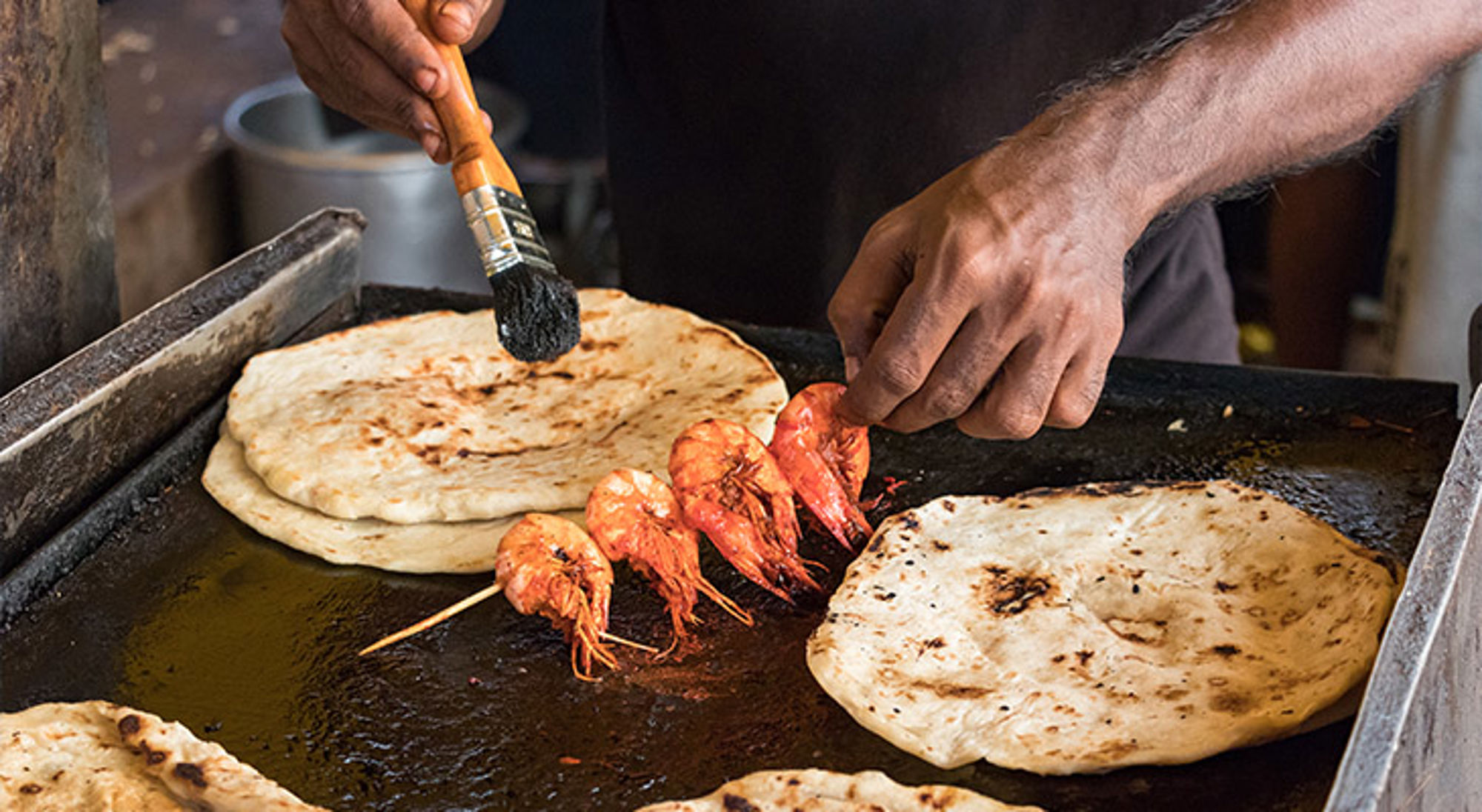 Streetfood in Colombo Garnalen en platbrood op een hete bakplaat, ingesmeerd met olie.