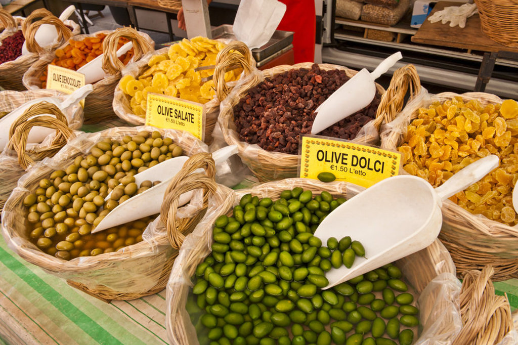 Marktkraam in Toscane met manden vol olijven en gedroogd fruit.