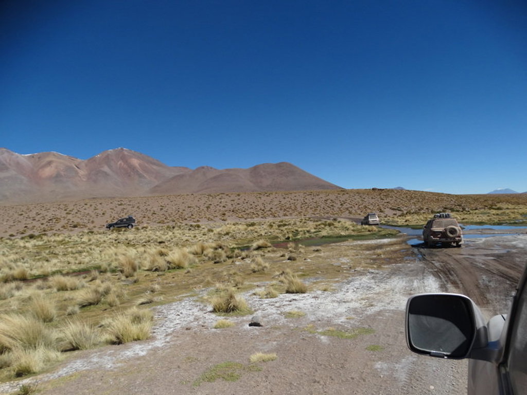 4x4-jeeps op een onverharde route door het Altiplano met bergen op de achtergrond, tijdens groepsrondreis Bolivia en Chili.