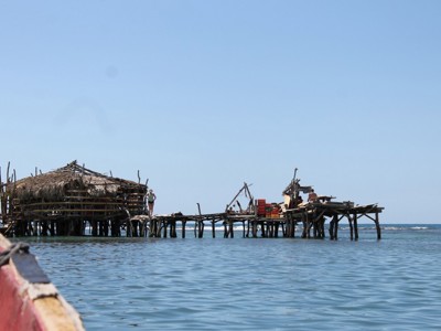 Vissershut op houten palen in zee bij Jamaica, gezien vanaf een boot.