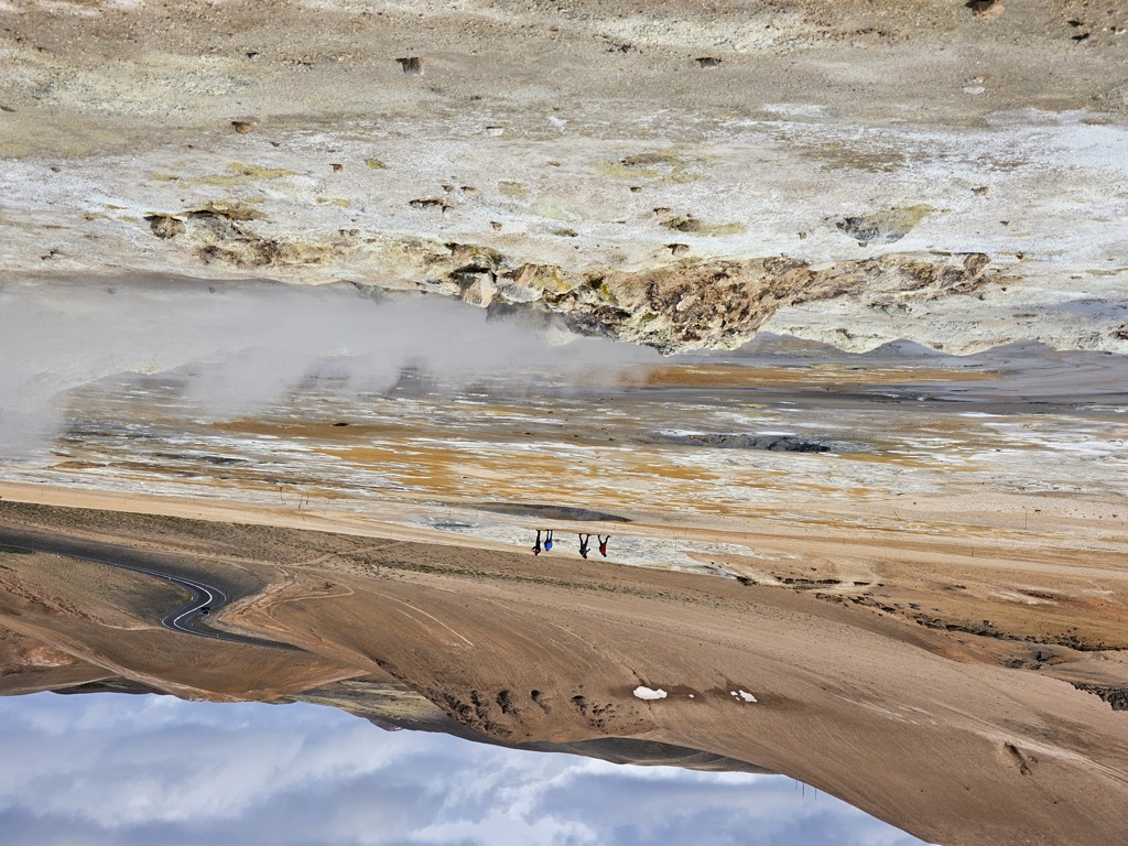 Wandelaars bij dampende geothermische bronnen in het vulkanische landschap van IJsland tijdens een groepsrondreis.