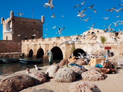 Vissershaven van Essaouira met oude vestingmuur, boten, visnetten en meeuwen in Marokko.