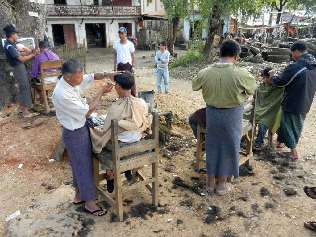 Straatkappers knippen mannen in de buitenlucht in Myanmar tijdens een familiereis.