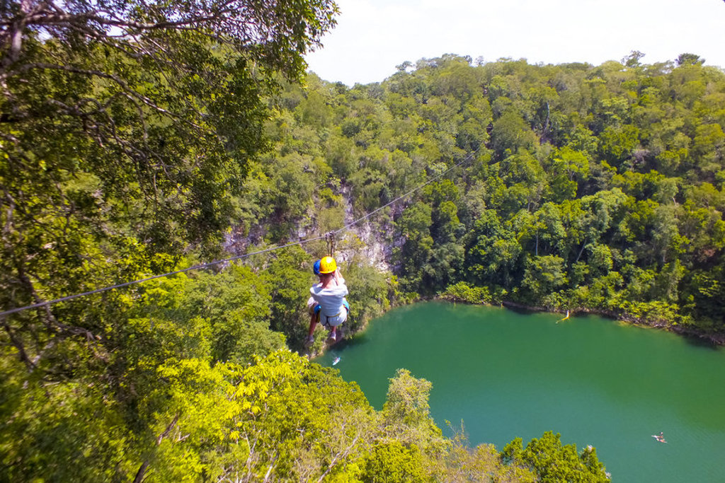 Ziplinen boven een groene lagune in de jungle tijdens een 22-35ers reis Mexico.