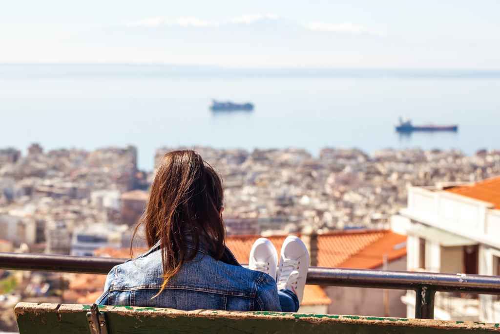 Meisje op uitkijkpunt met uitzicht over Thessaloniki en de zee, Noord-Griekenland.