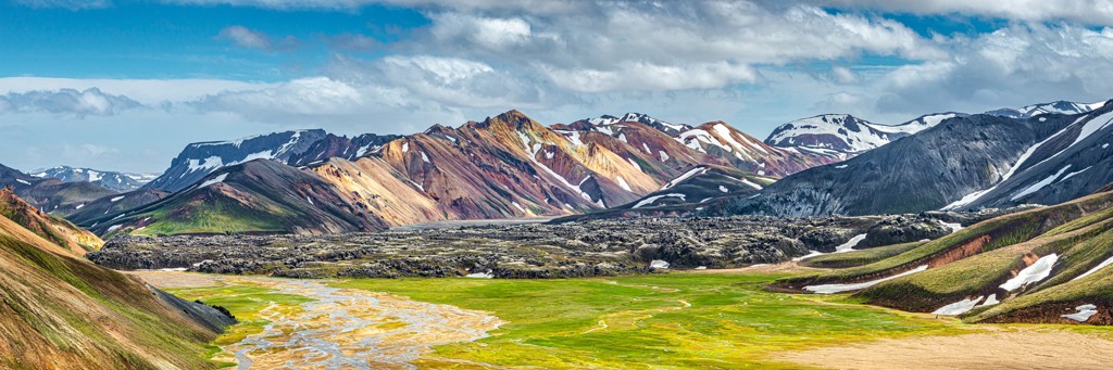Panorama van kleurrijke rhyolietbergen en groene vallei langs de Laugavegur Trail in IJsland.