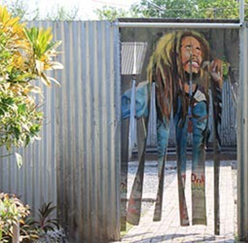 Muurschildering van Bob Marley op een metalen hek, Jamaica.