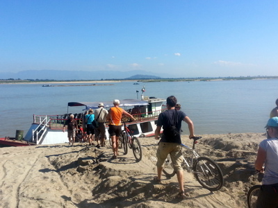 Fietsers stappen met hun fietsen aan boord van een boot op de Irrawaddy-rivier tijdens de Myanmar rondreis.