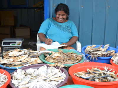 Vrouw noteert bestellingen bij kraam met gedroogde vis op een markt in Sri Lanka.