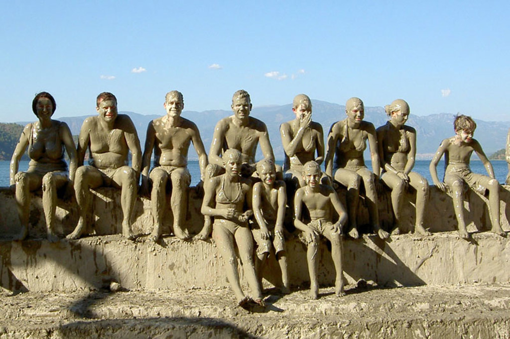 Gezin en andere reizigers onder modder na een modderbad aan de kust van Zuid-Turkije.