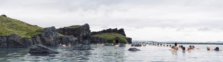 Bezoekers ontspannen in de geothermische Sky Lagoon met uitzicht op de Atlantische Oceaan bij Reykjavík, IJsland.