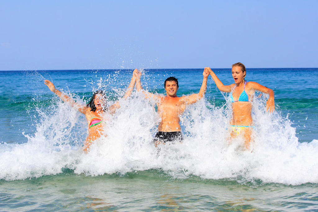 Gezin springt in de golven aan het strand tijdens Familiereis Griekenland Pop-Up.