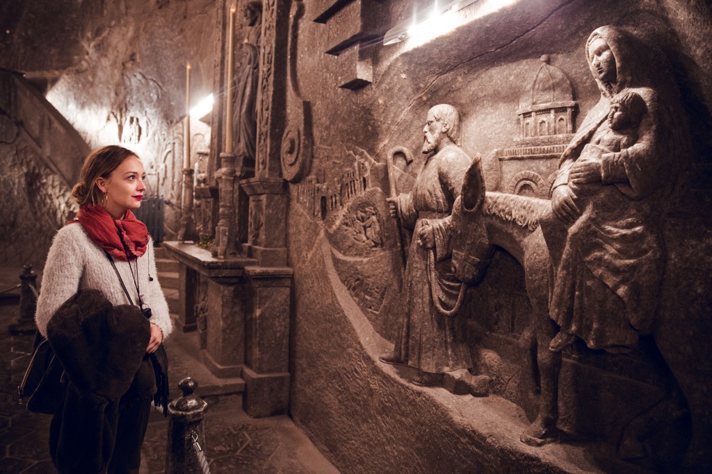 Bezoeker in de Wieliczka-zoutmijn bij reliëfs in zoutsteen tijdens een groepsrondreis Polen.